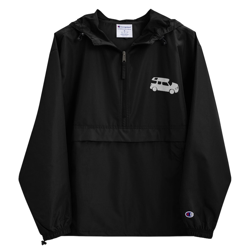 May include: Black Champion brand windbreaker jacket with a zipper closure and a white graphic of a car with a roof top tent on the front. The jacket has a hood and a small Champion logo on the right sleeve.