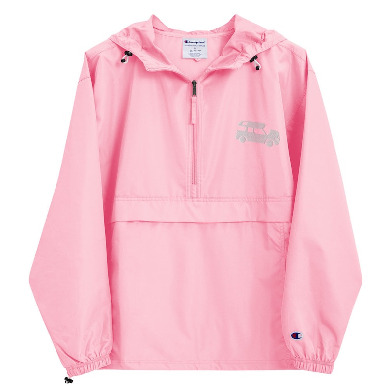 May include: A pink Champion brand windbreaker with a zipper closure and a small graphic of a car on the front. The windbreaker has a hood and a kangaroo pocket.