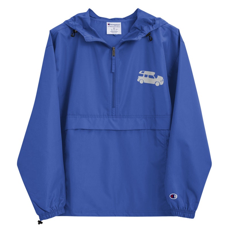 May include: A royal blue Champion windbreaker with a white logo on the left chest and a white silhouette of a car with a roof rack on the right chest.