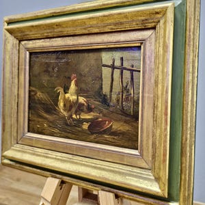 Peut inclure: Peinture encadr&eacute;e ancienne repr&eacute;sentant des poulets dans une ferme. L'&oelig;uvre pr&eacute;sente un coq et des poules pr&egrave;s d'une cl&ocirc;ture en bois et d'un bol. Le cadre dor&eacute; avec un bord int&eacute;rieur vert ajoute &agrave; l'esth&eacute;tique vintage.