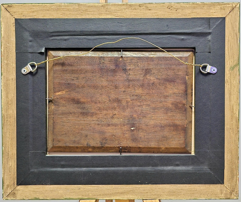 Peut inclure: Dos d'une &oelig;uvre encadr&eacute;e. Le cadre est en bois clair avec un bord noir. L'&oelig;uvre elle-m&ecirc;me est de couleur bois fonc&eacute;. Un fil est tendu &agrave; l'arri&egrave;re pour l'accrochage. Du mat&eacute;riel m&eacute;tallique est fix&eacute; au cadre.