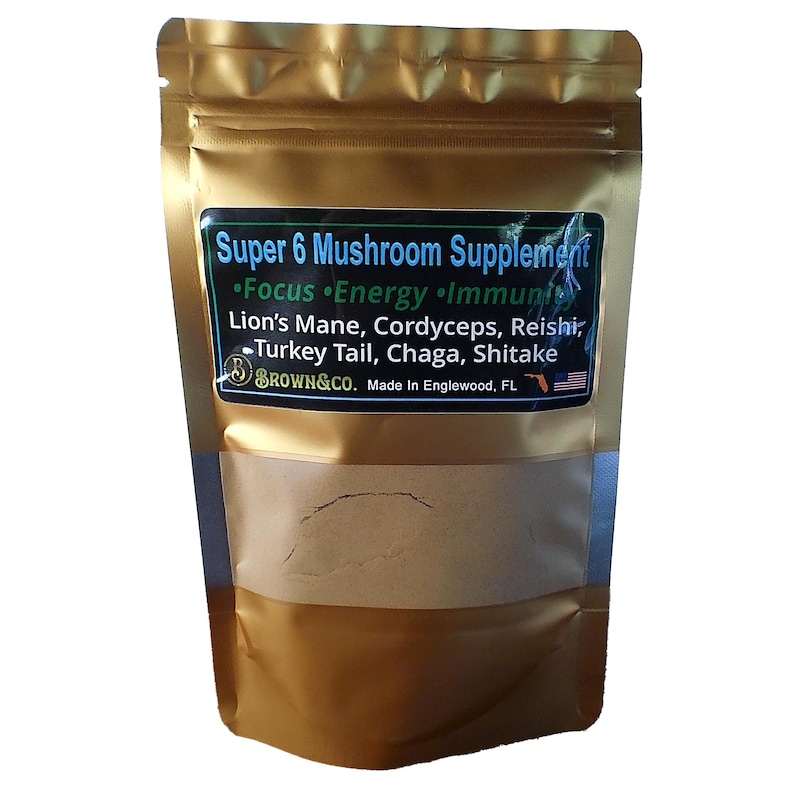 Peut inclure: Une pochette dor&eacute;e avec une &eacute;tiquette qui indique "Super 6 Mushroom Supplement &bull;Focus Energy Immunity Lion's Mane, Cordyceps, Reishi, Turkey Tail, Chaga, Shitake BROWN&CO. Made In Englewood, FL". La pochette contient une poudre brune.