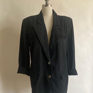 May include: A black blazer with a single button closure and two pockets. The blazer has a relaxed fit and a slightly longer length.