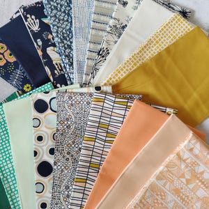 May include: A selection of fabric swatches fanned out, displaying a range of patterns and colours. The fabrics feature floral, geometric, and abstract designs in navy, green, yellow, and peach hues. The swatches are arranged to show the different textures and styles.