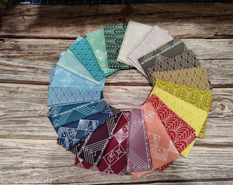 May include: A set of 18 fabric squares with geometric patterns in various shades of blue, green, yellow, orange, red, and purple. The squares are arranged in a circle on a wooden surface.