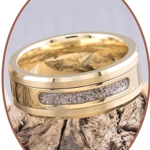 May include: A gold wedding band with a thin band of gray sand embedded in the center.