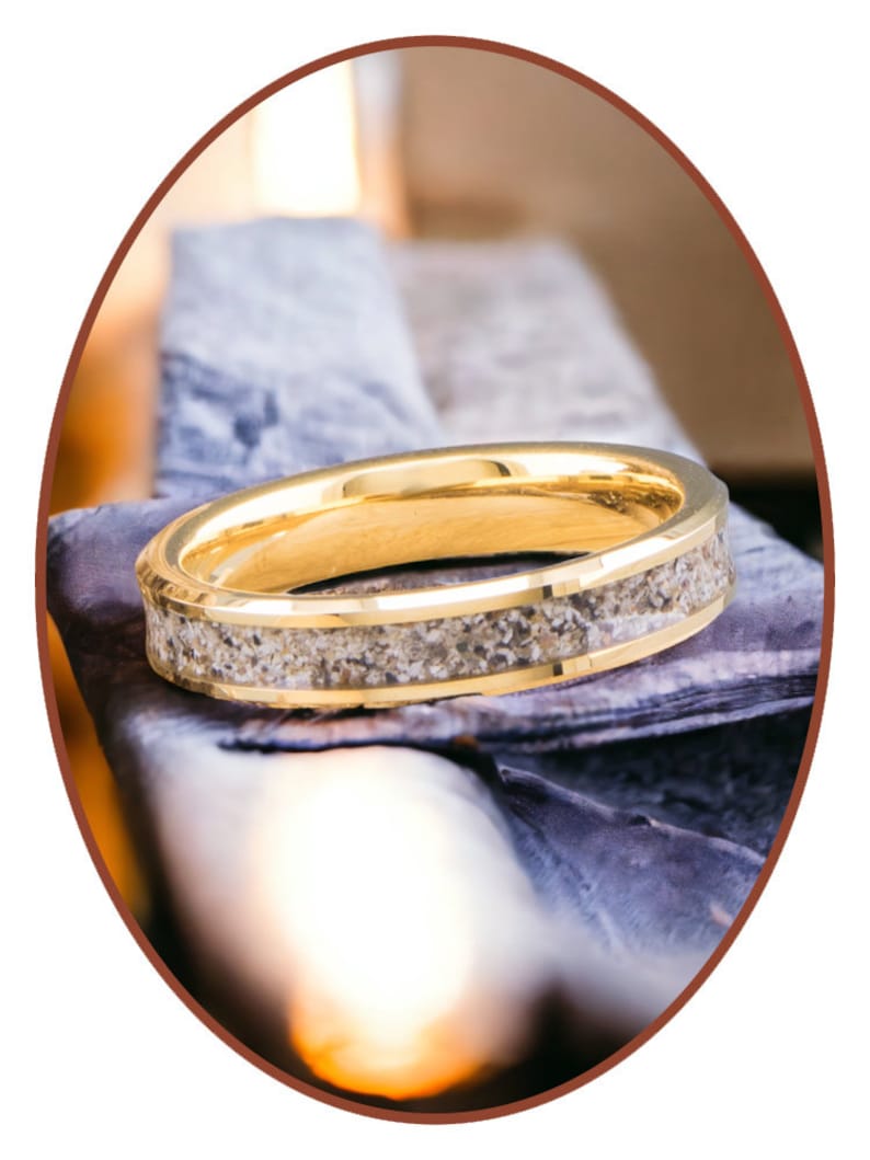 Op de afbeelding: Een gouden ring met een band van zand ingebed in het metaal.