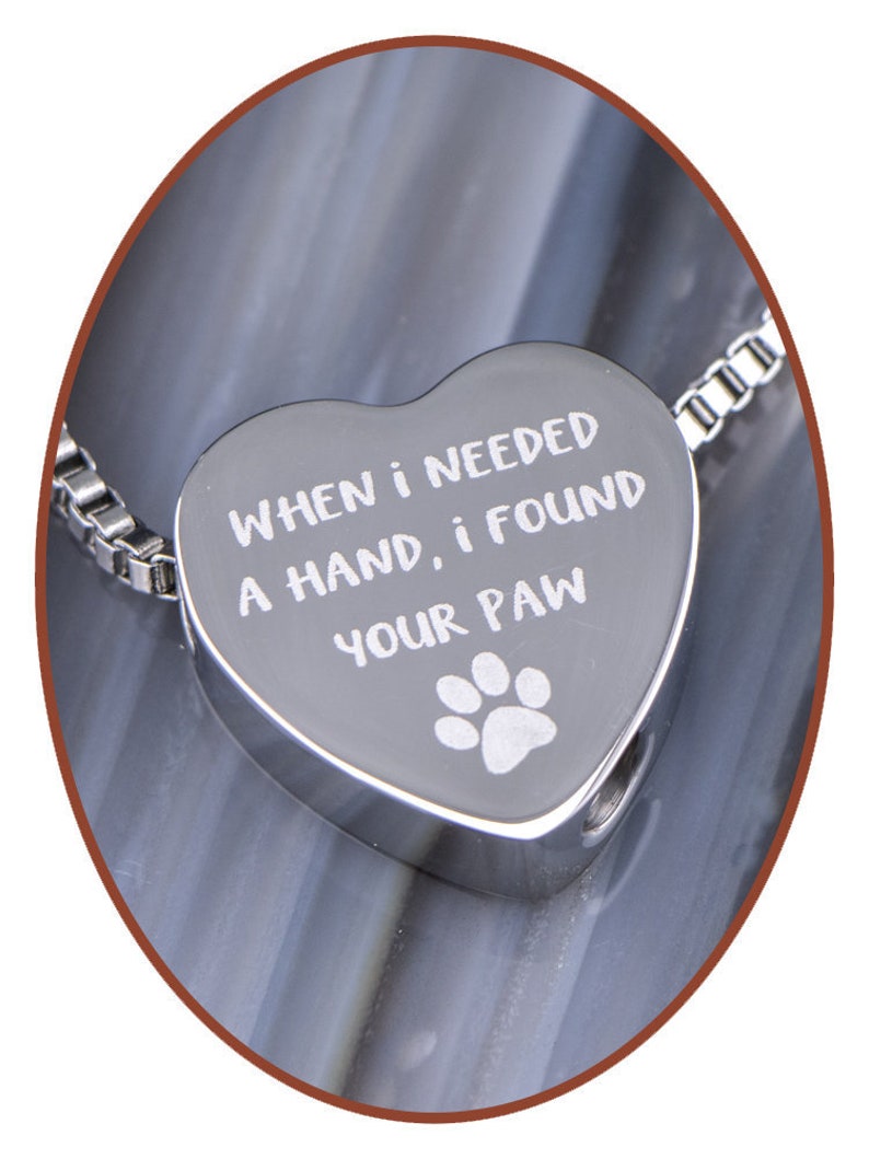 May include: Silver heart-shaped pendant necklace with a chain. The pendant has the inscription "When I needed a hand, I found your paw" and a paw print.