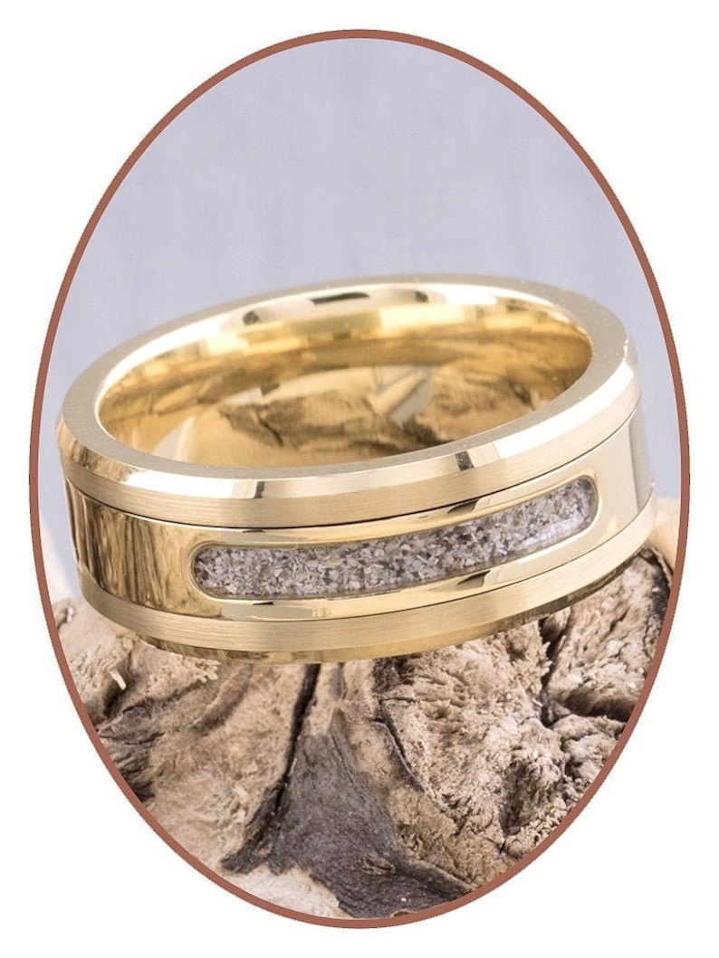 May include: A gold wedding band with a thin band of gray sand embedded in the center.