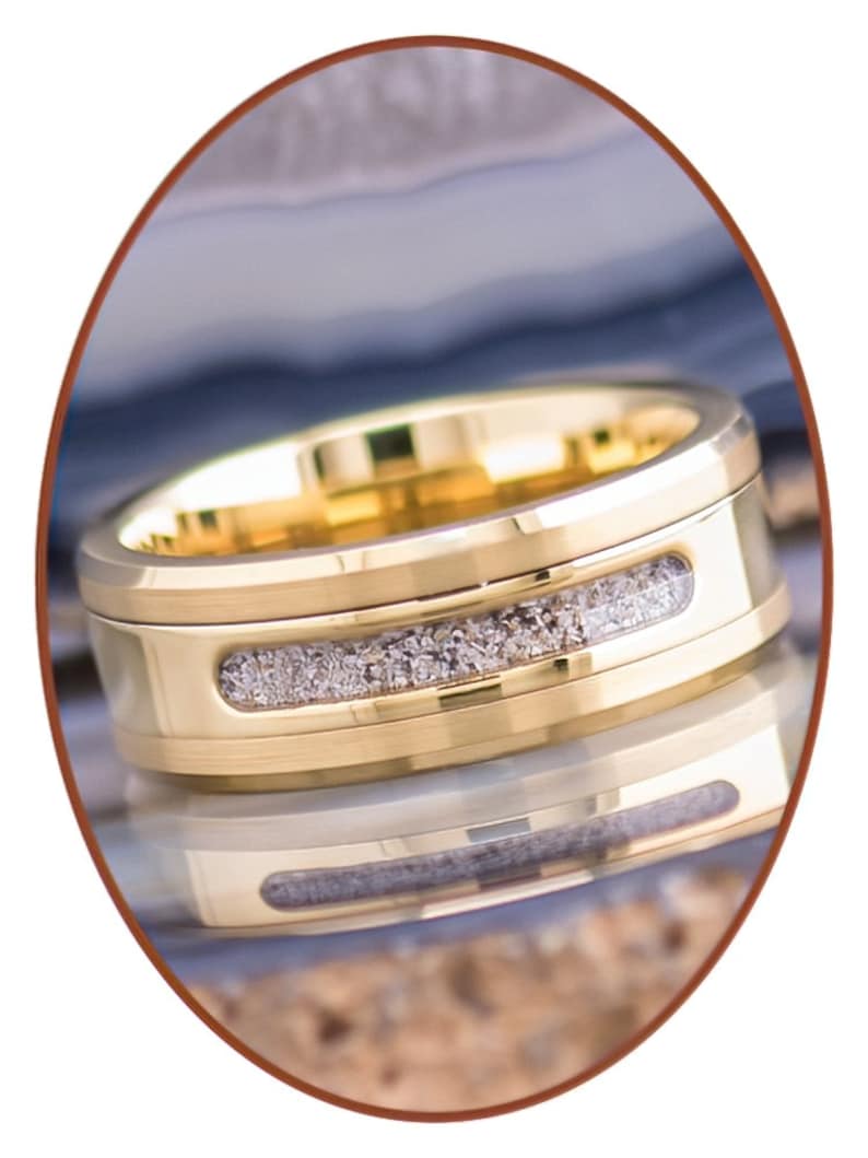 May include: A gold wedding band with a thin band of grey inlay.