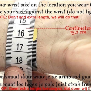 K&ouml;nnte beinhalten: Ein wei&szlig;es Ma&szlig;band, das um ein Handgelenk gewickelt ist, um zu zeigen, wie man die Handgelenksgr&ouml;&szlig;e f&uuml;r ein Armband misst. Das Band zeigt 15,2 cm oder 6 Zoll an. Der Text lautet "Messen Sie Ihre Handgelenksgr&ouml;&szlig;e an der Stelle, an der Sie das Armband tragen. Messen Sie Ihre Gr&ouml;&szlig;e am Handgelenk (nicht festziehen). HINWEIS: F&uuml;gen Sie keine zus&auml;tzliche L&auml;nge hinzu, das &uuml;bernehmen wir!"