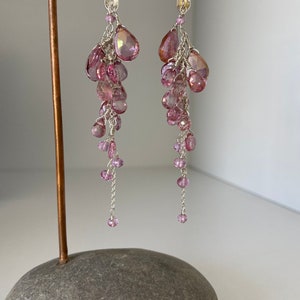 May include: A pair of long, dangling earrings with pink gemstone beads and silver chain accents.