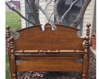 May include: A wooden headboard with a curved top and turned posts. The headboard is a rich brown color and has a simple, elegant design.