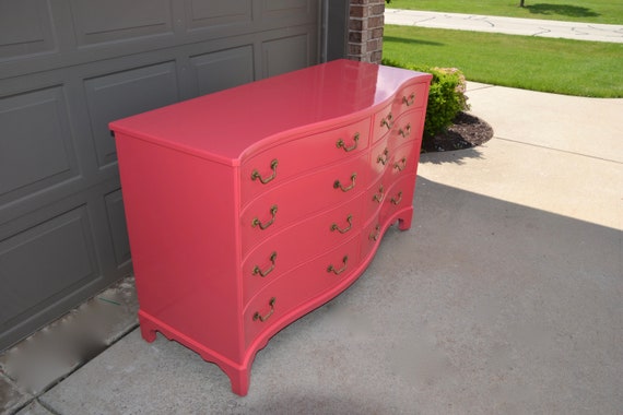 bright red dresser New Uses bright-red painted dresser with rounded sides and three large drawers, red lamp sitting on top of dresser and tan- and white-striped wallpaper in the background