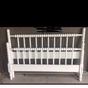 May include: White wooden bed frame with a headboard featuring a series of turned spindles with ball finials.