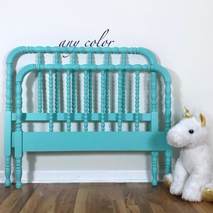 May include: A teal blue wooden bed frame with a spindle design. The bed frame is in front of a white wall and a wooden floor. The text "any color" is written above the bed frame.