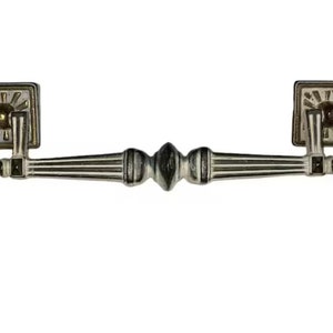 May include: Antique silver-toned drawer pull with a decorative design. The pull features square backplates with a sunburst pattern and a central handle with a detailed, ridged design. A classic hardware piece.
