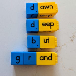 May include: Blue and yellow word blocks spelling out "dawn", "deep", "but", and "grand". The blocks are arranged in rows, with the blue blocks on the left and the yellow blocks on the right. The letters are in black.