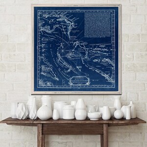 Puede incluir: Un mapa vintage azul y blanco de las Bahamas, enmarcado en un marco de madera claro. El mapa muestra las islas de las Bahamas, incluyendo el "Banco Grande de Bahama" y "Luchadas de los Lucayos".