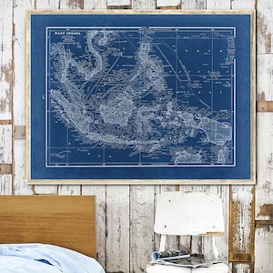 May include: A vintage blue and white map of the East Indies, framed in a light wood frame. The map shows the islands of Indonesia, Malaysia, and the Philippines.