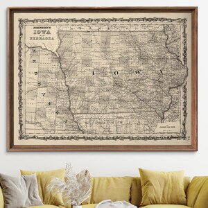 May include: A vintage map of Iowa, Nebraska, and parts of surrounding states, printed in black and white on a cream-colored paper. The map is framed in a brown wood frame and has a decorative border.