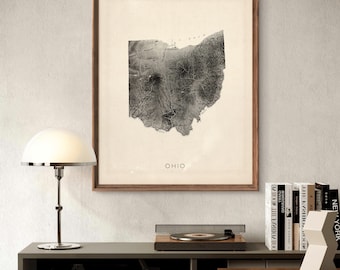 May include: A black and white vintage map print of the state of Ohio in a brown wood frame. The map is titled "Ohio" and is displayed on a wall above a wooden desk with a record player and books.