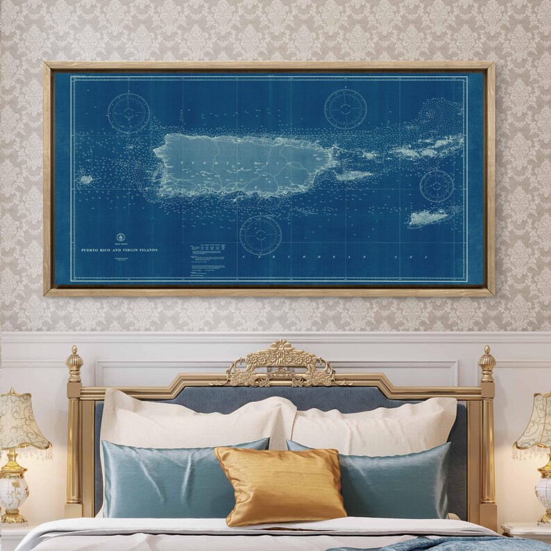 May include: A vintage nautical chart of Puerto Rico and the Virgin Islands, printed on blue paper with white lines and text. The chart is framed in a light wood frame and is hanging on a wall with a white and gray patterned wallpaper.