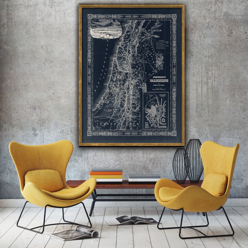 May include: A vintage map of Palestine, framed in gold, hangs on a gray wall. Two yellow armchairs with black metal frames are positioned in front of the map, facing each other. A wooden coffee table sits between the chairs.