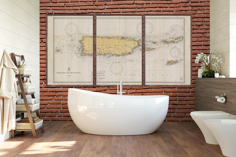 May include: A bathroom interior with a white freestanding bathtub, a white toilet, and a brick wall with a framed vintage map of Puerto Rico.