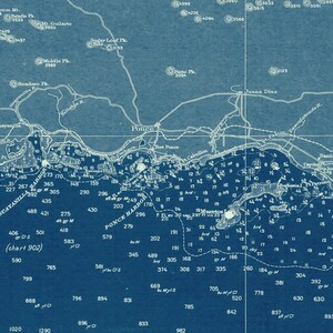 May include: A vintage nautical chart of Ponce Harbor in Puerto Rico, showing depths in feet and nautical markers. The chart is printed on blue paper with white text and lines.