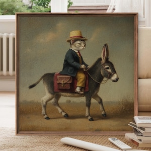 May include: A framed vintage-style print depicts a cat dressed in a suit and hat riding a donkey. The cat wears a dark blue jacket, yellow pants, and a red tie. The donkey is gray, and the background is a muted landscape.