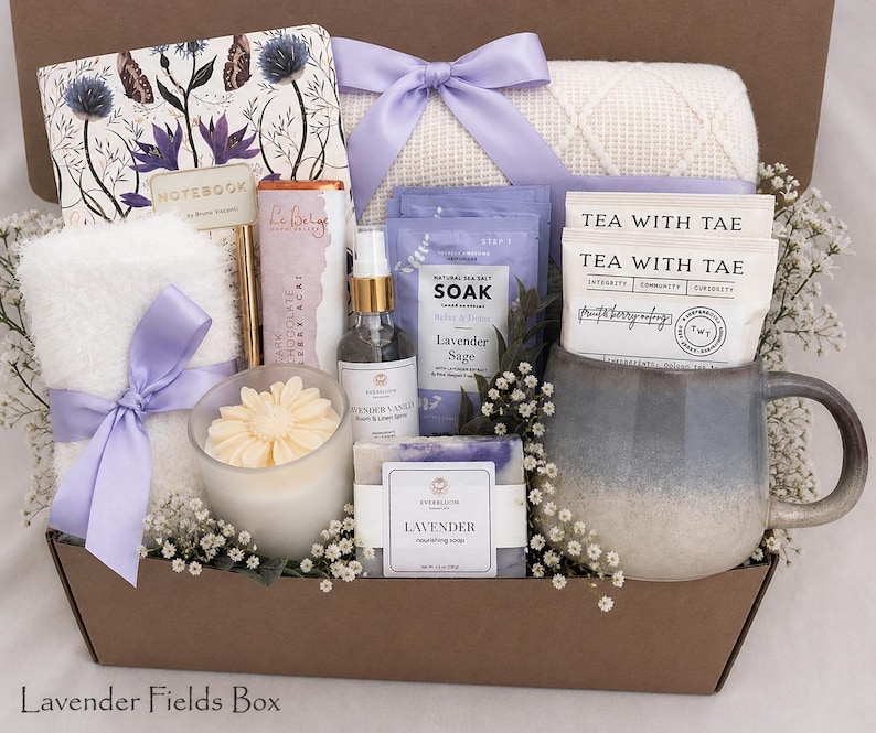 May include: A gift box containing a floral notebook, a white waffle-knit blanket with a lavender ribbon, a chocolate bar, a lavender vanilla spray, a lavender sage soak, a lavender soap, a flower-shaped candle, and a mug with two Tea With Tae packets.