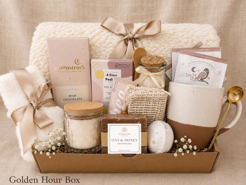 Puede incluir: Una cesta de regalo que contiene una manta texturizada de color crema con una cinta de sat&eacute;n, una barra de chocolate con leche Moonstruck, un kit de pedicura de 4 pasos, un frasco de vidrio con tapa de corcho, una taza, una cuchara dorada y jab&oacute;n de avena y miel.