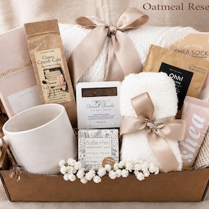 Puede incluir: Una caja de regalo etiquetada como Oatmeal Reset Box que contiene una taza de cer&aacute;mica blanca, una cuchara de cobre, una bolsa de Classic Crumb Cake, un jab&oacute;n Charmed Elements, una bomba de ducha Sofie+Peri, un art&iacute;culo blanco difuso y crema de karit&eacute;.