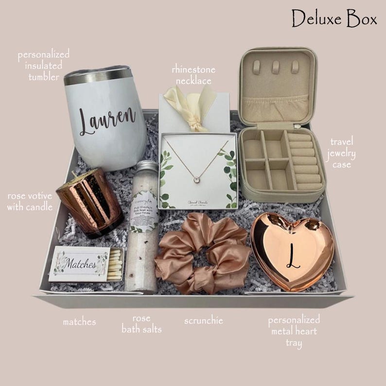 May include: A gift box with a white insulated tumbler with a name, a rose gold votive candle, a rhinestone necklace, a travel jewelry case, rose bath salts, a scrunchie, matches, and a personalized metal heart tray.