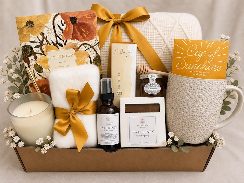 Puede incluir: Una cesta de regalo que contiene un cuaderno floral, un art&iacute;culo blanco y difuso con un lazo dorado, una vela, una loci&oacute;n corporal Oat Honey, una pastilla de jab&oacute;n Oat Honey, una barra de chocolate, un tarro de miel con cuchara y una taza.