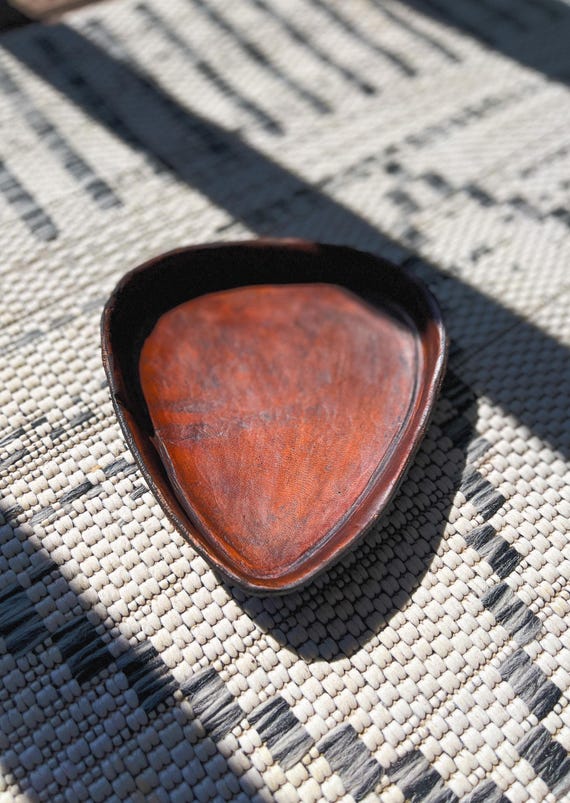 Hand-stitched vegetable-tanned leather valet tray customized with a guitar/musician motif — a tactile, aging-beautifully EDC piece that feels genuinely crafted, not printed.