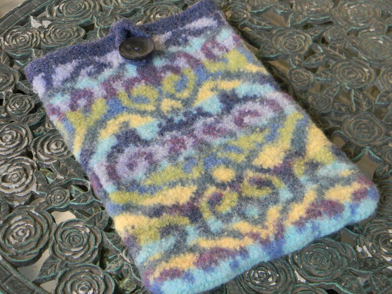 May include: A blue, yellow and purple knitted phone case with a decorative button.