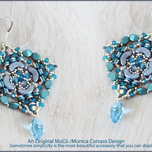 May include: A pair of handcrafted earrings with a floral design. The earrings feature a combination of teal, light blue, and silver beads, with a teardrop-shaped crystal pendant. The text "An Original MoCò / Monica Corsaro Design" is visible.