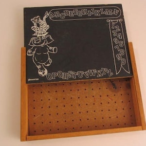 May include: A vintage wooden chalkboard with a black surface and white chalk drawings of an elephant, a tiger, and the alphabet. The chalkboard has a pegboard on the back.
