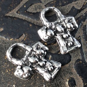 Puede incluir: Dos encantos Ankh de plata con un acabado texturizado. Los encantos tienen un bucle en la parte superior para sujetarlos a un collar o pulsera.