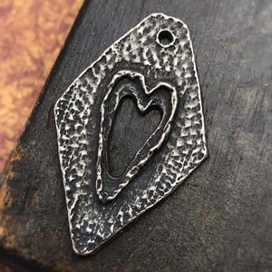 May include: A silver charm in the shape of a diamond with a heart cut out of the center. The charm has a textured surface and a hole at the top for attaching to a necklace or bracelet.