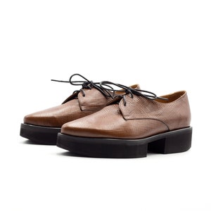 K&ouml;nnte beinhalten: Braune Lederschuhe mit Schn&uuml;rung und Plateau-Sohle.