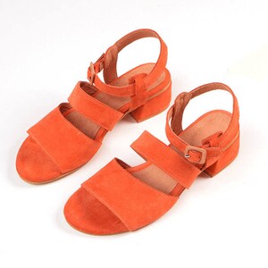 K&ouml;nnte beinhalten: Zwei Paar orangefarbene Wildledersandalen mit Schnallen.