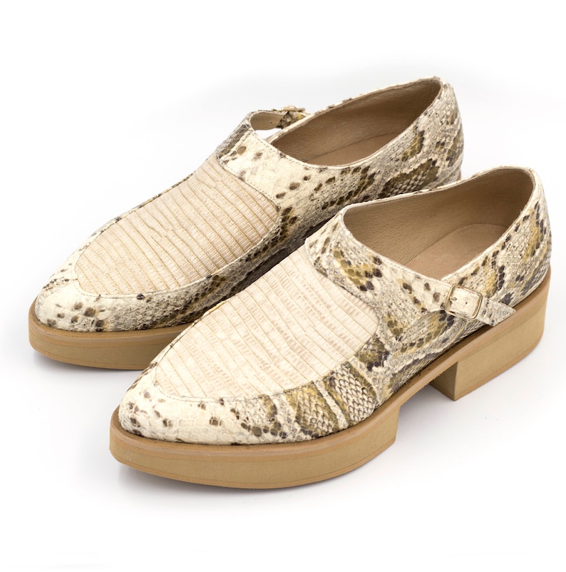 Puede incluir: Un par de zapatos de piel de serpiente beige y marr&oacute;n con una correa de hebilla y una suela de plataforma gruesa.