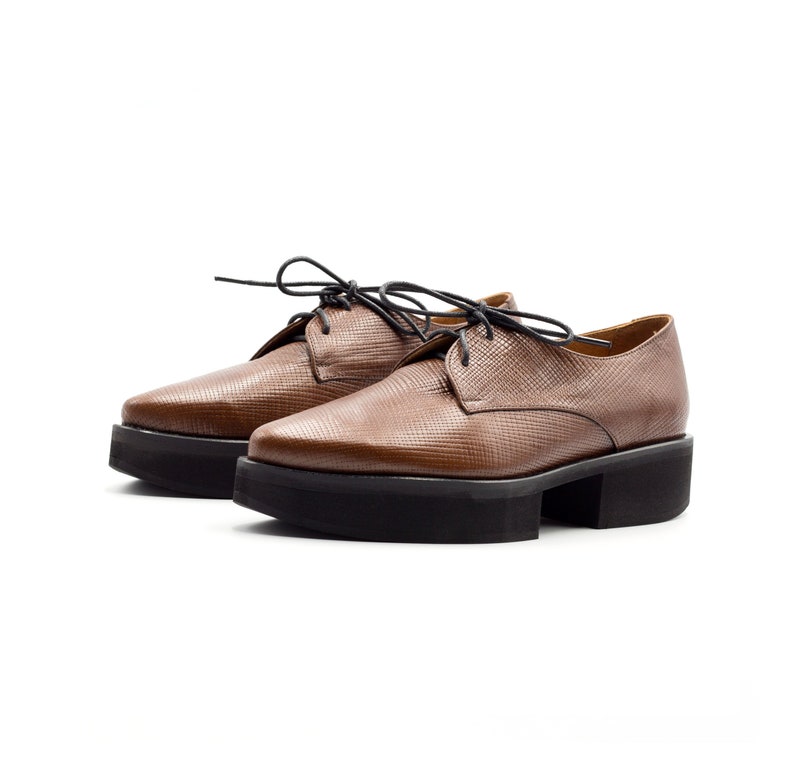 K&ouml;nnte beinhalten: Braune Lederschuhe mit Schn&uuml;rung und Plateau-Sohle.