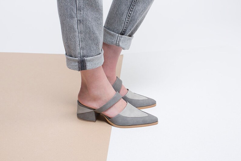 May include: Gray suede heeled mules with a pointed toe and a double strap across the foot.