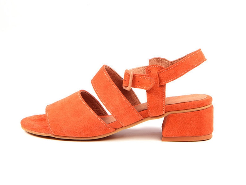 K&ouml;nnte beinhalten: Orangefarbene Sandalen aus Wildleder mit Absatz, Schnalle und offener Zehenpartie.