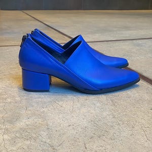 May include: A pair of bright blue leather heeled shoes with a pointed toe and a block heel.