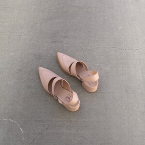 May include: A pair of light brown leather heeled sandals with ankle straps. The sandals have a pointed toe and a chunky heel.
